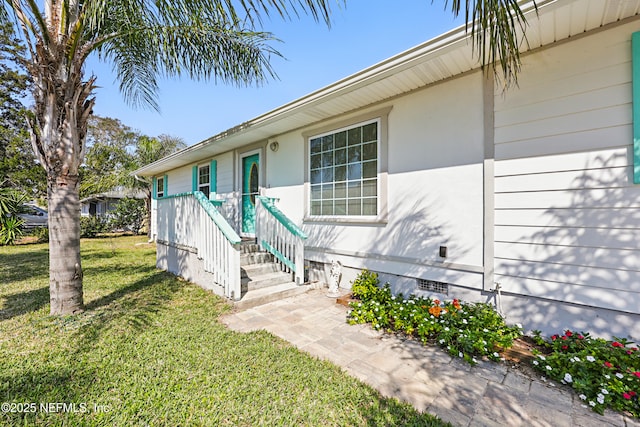 entrance to property with crawl space and a lawn