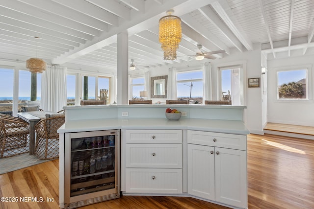 kitchen featuring wine cooler, a healthy amount of sunlight, beam ceiling, and light wood-style floors