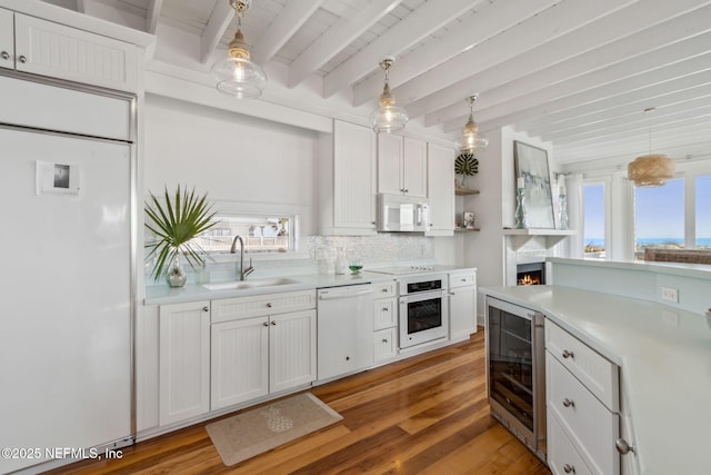 kitchen with light countertops, white appliances, wine cooler, and a sink