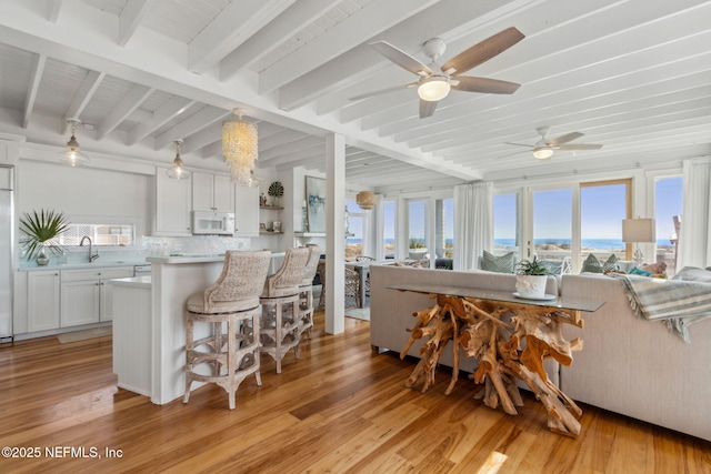 kitchen with white microwave, decorative backsplash, a breakfast bar, and a wealth of natural light