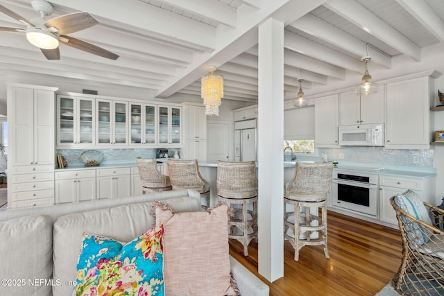 kitchen featuring white appliances, wood finished floors, white cabinetry, light countertops, and tasteful backsplash