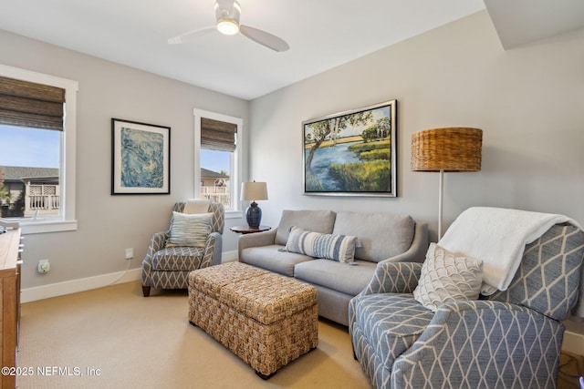 living room featuring a ceiling fan, light carpet, and baseboards