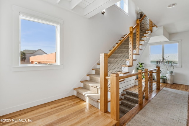 stairway with plenty of natural light, baseboards, and wood finished floors