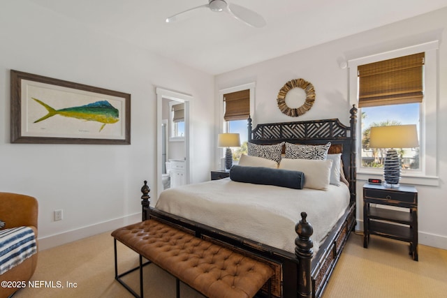 bedroom with light colored carpet, multiple windows, baseboards, and ensuite bathroom