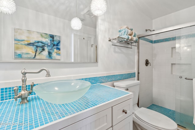 full bathroom featuring a stall shower, tile walls, vanity, and toilet