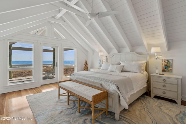 bedroom featuring lofted ceiling with beams, a water view, wood finished floors, and access to exterior