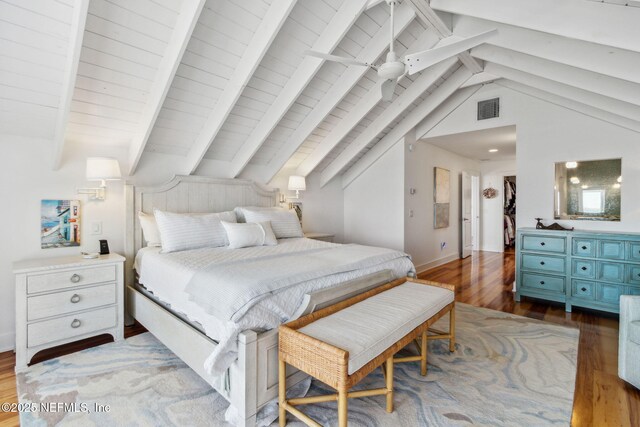 bedroom featuring vaulted ceiling with beams, wood finished floors, visible vents, and baseboards