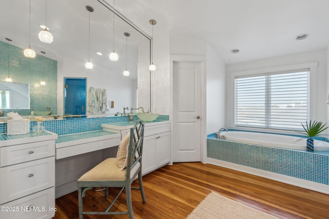 bathroom featuring lofted ceiling, a garden tub, wood finished floors, and vanity