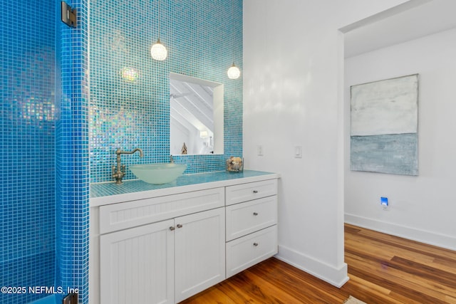 full bathroom with backsplash, vanity, baseboards, and wood finished floors