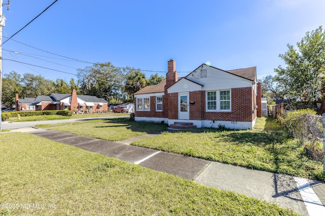 bungalow-style home featuring a chimney, crawl space, fence, a front lawn, and brick siding