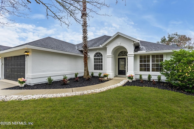 ranch-style house featuring an attached garage, a shingled roof, driveway, stucco siding, and a front yard