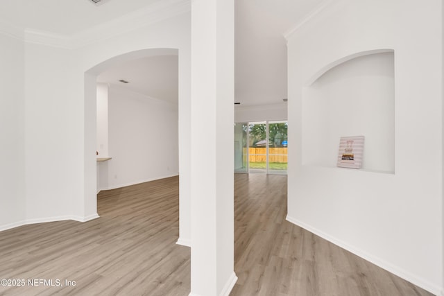 interior space with light wood finished floors, baseboards, and crown molding