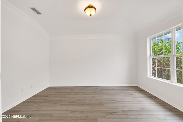 empty room with baseboards, visible vents, wood finished floors, and ornamental molding