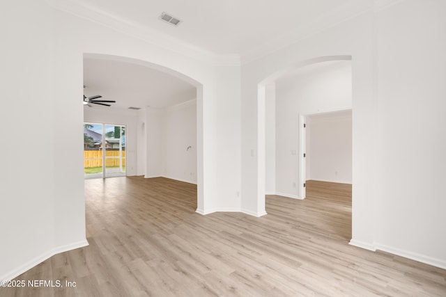 empty room featuring ornamental molding, light wood-type flooring, visible vents, and ceiling fan