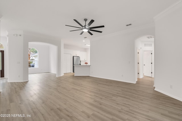 unfurnished living room featuring arched walkways, visible vents, crown molding, and light wood-style flooring