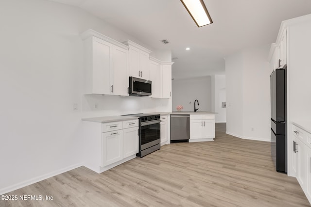 kitchen featuring appliances with stainless steel finishes, white cabinets, and light countertops