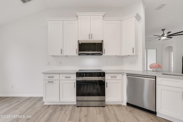 kitchen with appliances with stainless steel finishes, white cabinets, light countertops, and light wood-style floors