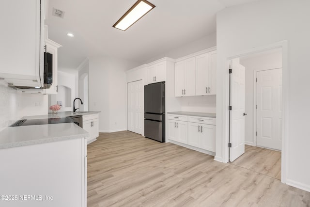 kitchen featuring light countertops, visible vents, light wood-style flooring, white cabinetry, and black appliances