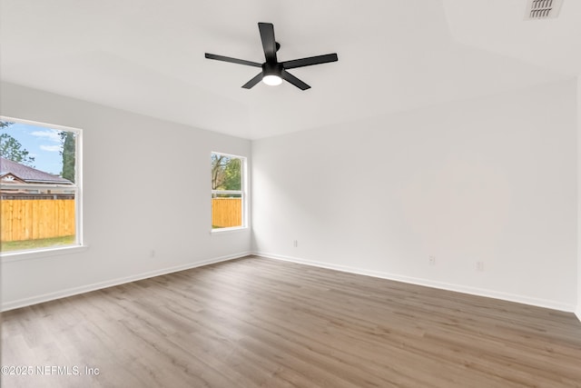 spare room with ceiling fan, wood finished floors, visible vents, and baseboards