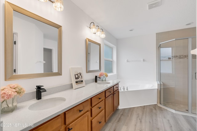 bathroom featuring a bath, a stall shower, a sink, and visible vents