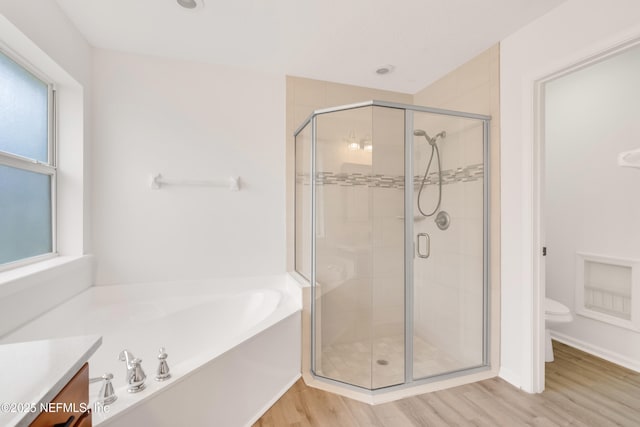 bathroom with toilet, wood finished floors, vanity, a shower stall, and a bath