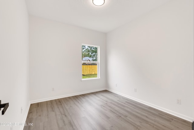 spare room featuring light wood-type flooring and baseboards