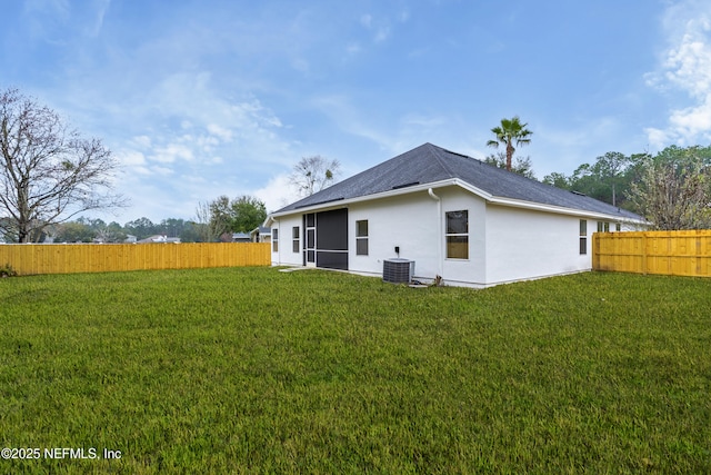 back of property featuring a fenced backyard, a lawn, and central AC