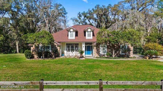 new england style home with a shingled roof, a porch, and a front yard