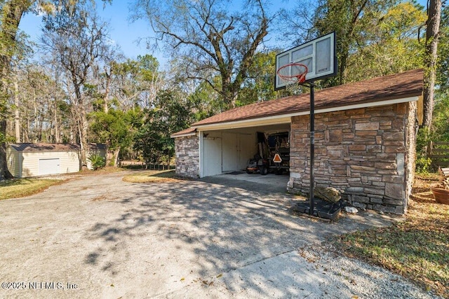 garage with driveway and a storage shed