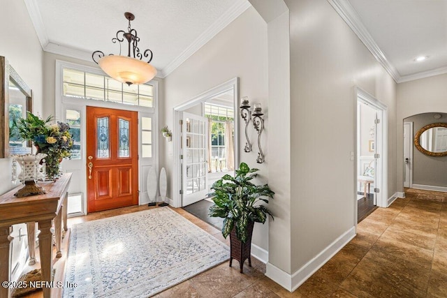 foyer entrance featuring baseboards, arched walkways, and crown molding