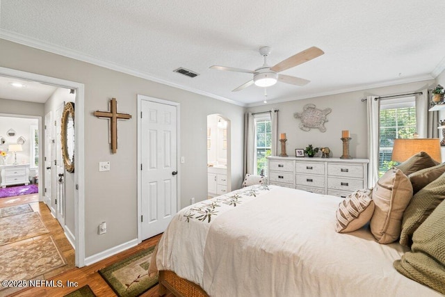 bedroom featuring ornamental molding, visible vents, multiple windows, and wood finished floors