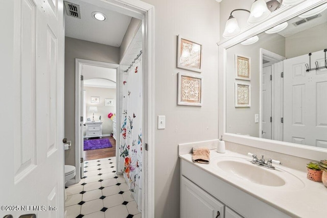 bathroom featuring toilet, vanity, and visible vents