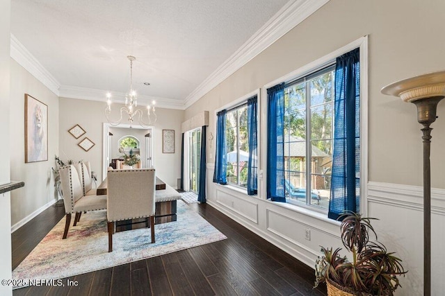 dining room with ornamental molding, a chandelier, dark wood finished floors, and a decorative wall