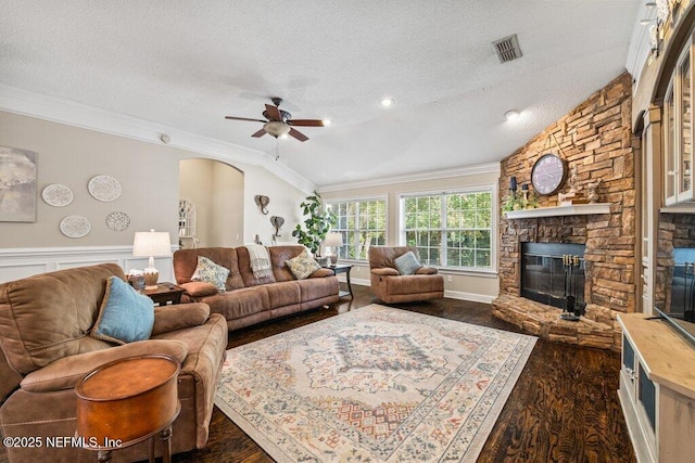 living area with lofted ceiling, crown molding, a stone fireplace, and a textured ceiling