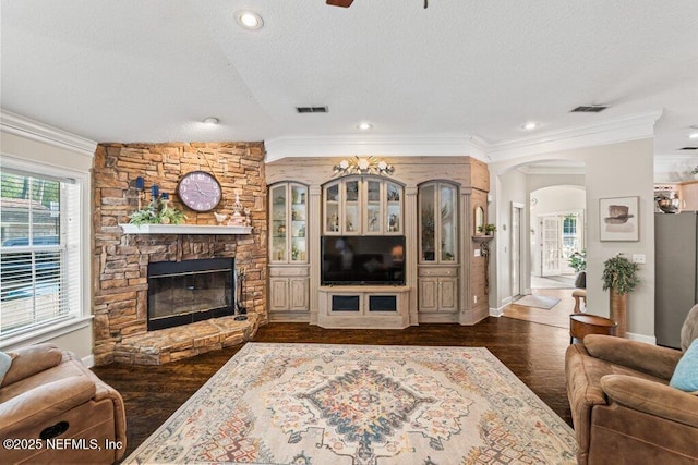 living room with dark wood-style floors, a fireplace, ornamental molding, and a textured ceiling