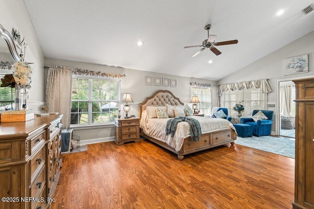 bedroom with vaulted ceiling, multiple windows, wood finished floors, and a ceiling fan