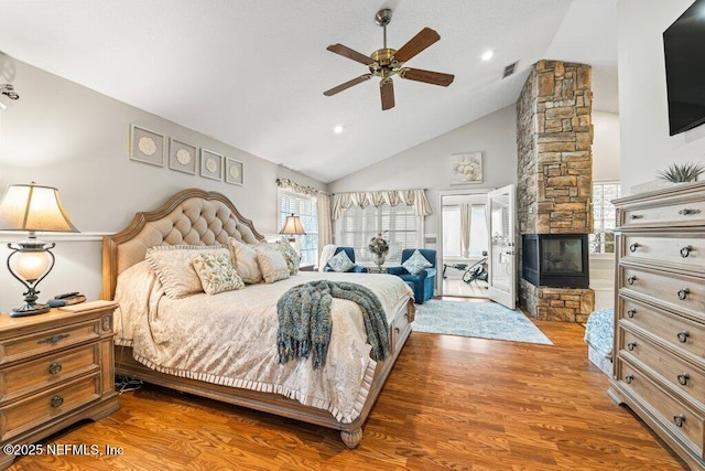 bedroom with a fireplace, visible vents, a ceiling fan, wood finished floors, and high vaulted ceiling