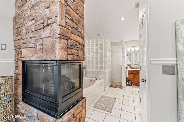 bathroom featuring a garden tub, a fireplace, vanity, visible vents, and tile patterned floors