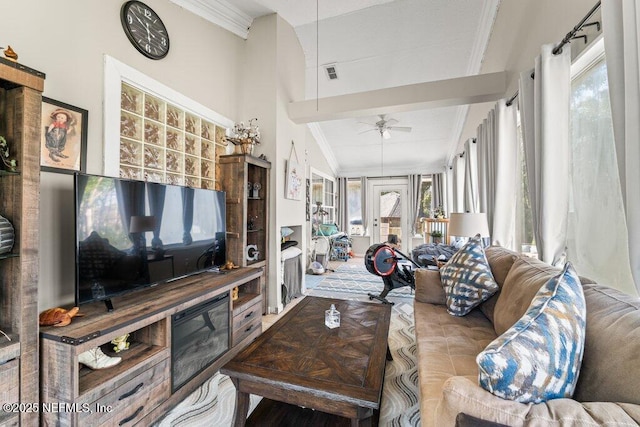 living area featuring a towering ceiling, visible vents, ornamental molding, and a ceiling fan