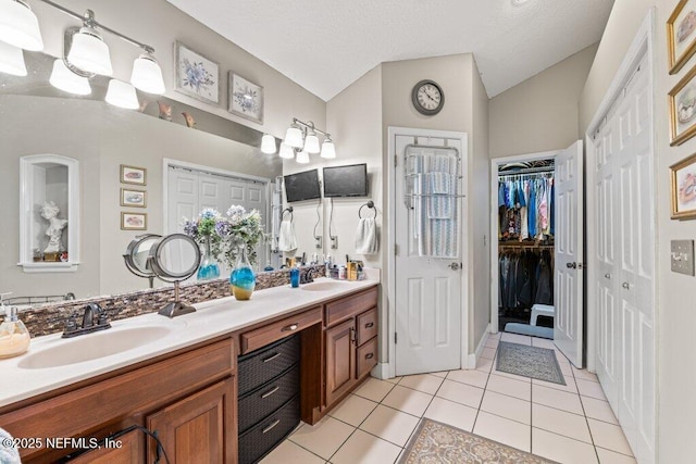 full bathroom featuring lofted ceiling, tile patterned flooring, double vanity, and a sink