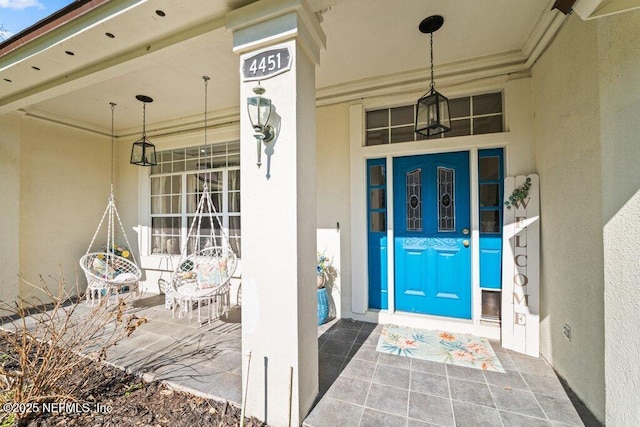 view of exterior entry featuring a porch and stucco siding