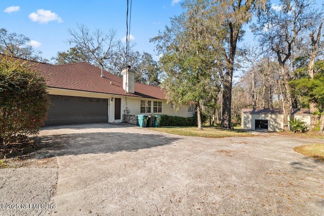 ranch-style home featuring driveway, a chimney, an attached garage, and stucco siding