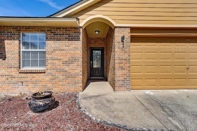 property entrance featuring a garage and brick siding