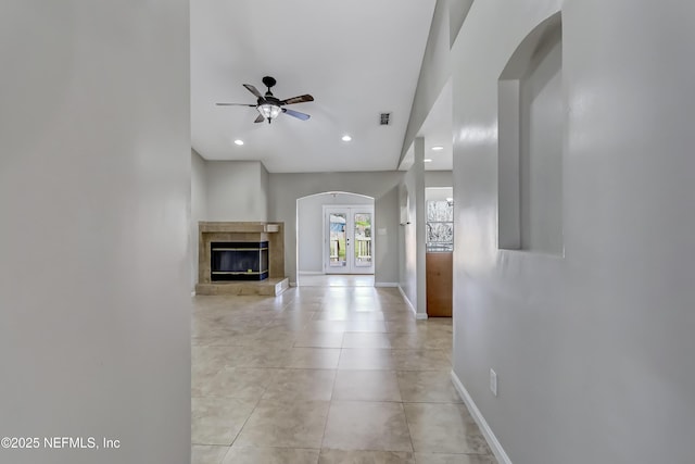 unfurnished living room featuring arched walkways, french doors, recessed lighting, light tile patterned flooring, and baseboards