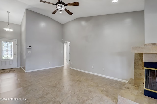 unfurnished living room with a ceiling fan, tile patterned flooring, a fireplace, and baseboards