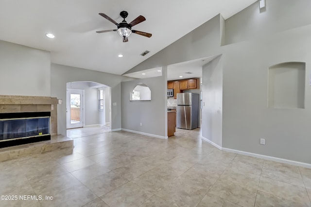 unfurnished living room with ceiling fan, a tile fireplace, visible vents, and baseboards