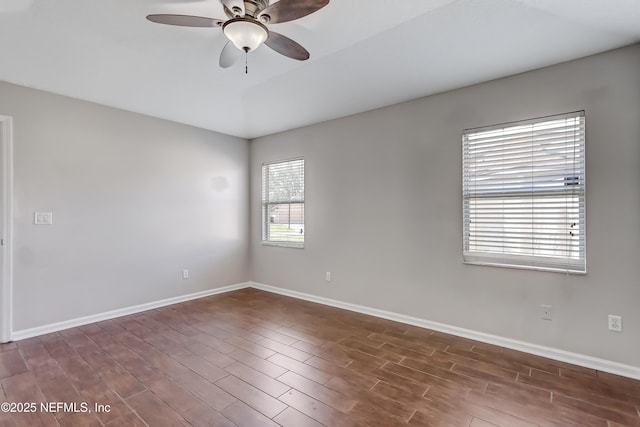 spare room featuring ceiling fan, dark wood-style flooring, and baseboards