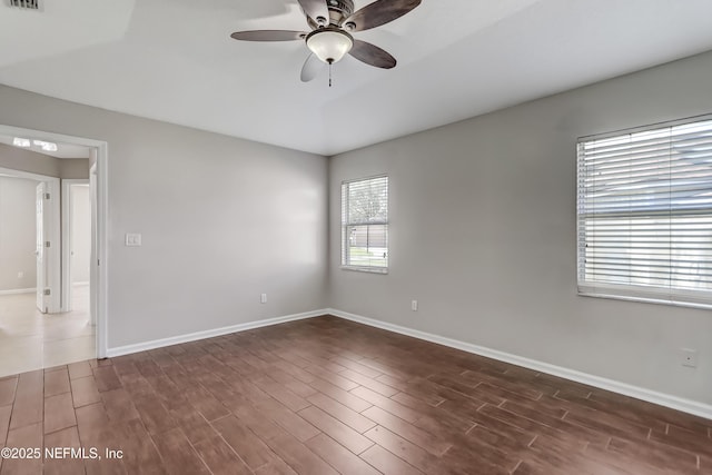 unfurnished room with visible vents, dark wood finished floors, baseboards, and ceiling fan