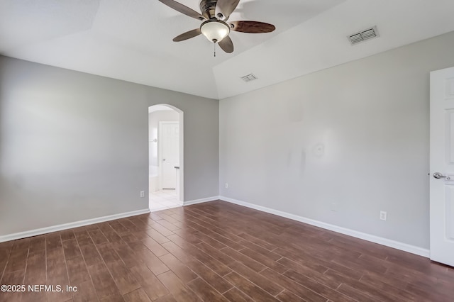 spare room featuring baseboards, visible vents, arched walkways, and wood finished floors