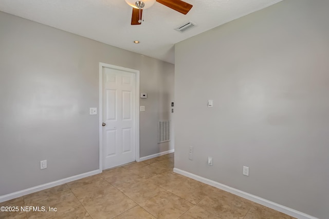 unfurnished room with baseboards, light tile patterned floors, visible vents, and a ceiling fan